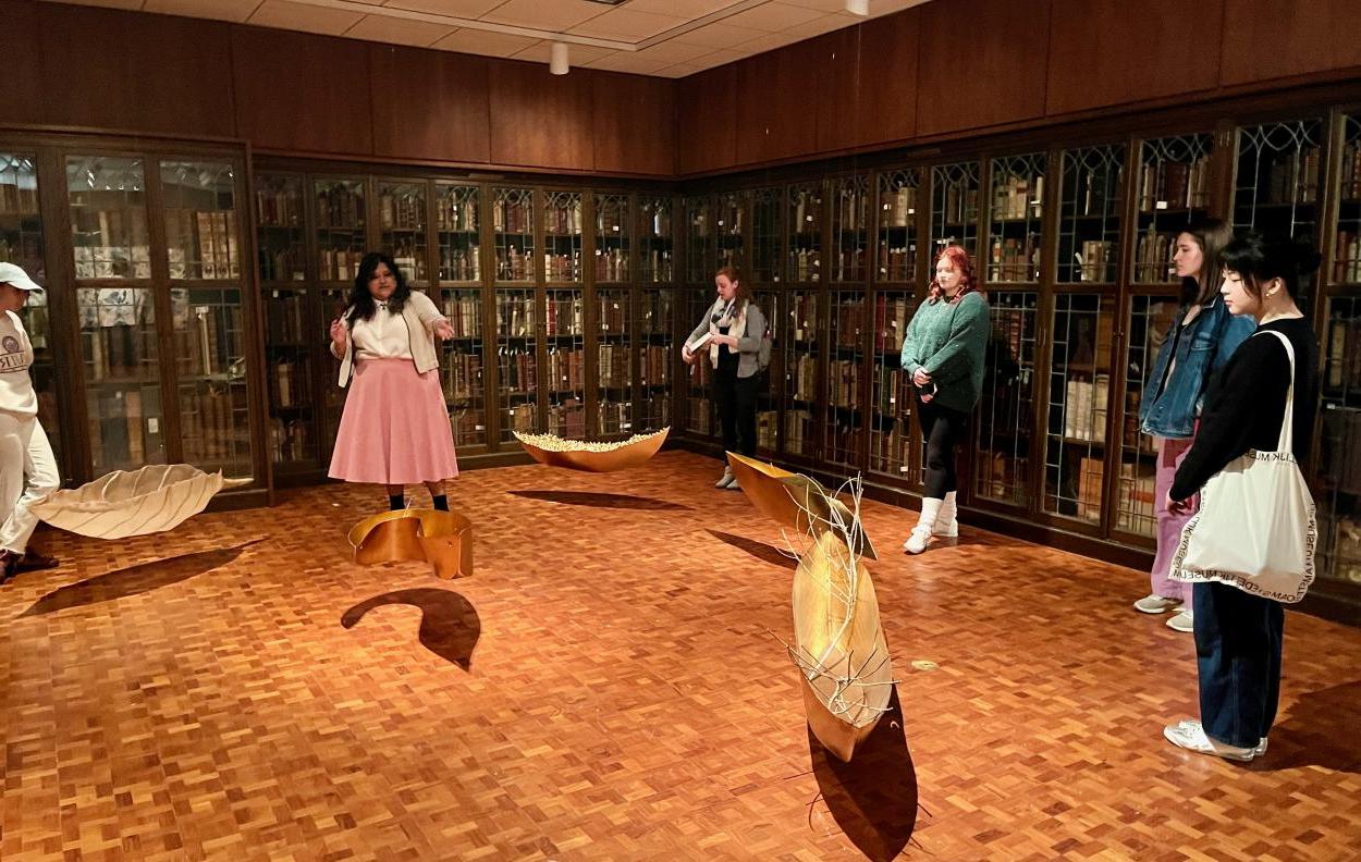 约瑟琳·加西亚带领周五发现之旅 group through the Cecilia Paredes exhibition; she points to the gilded boat sculptures hanging in the gallery